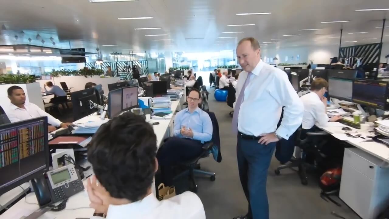 The man is talking to his colleagues in the office