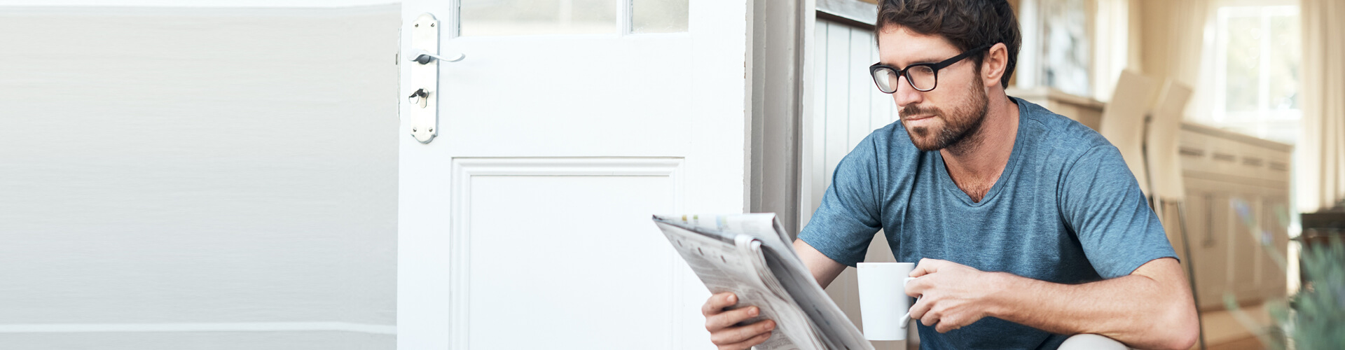 Man reading the newspaper and drinking coffee