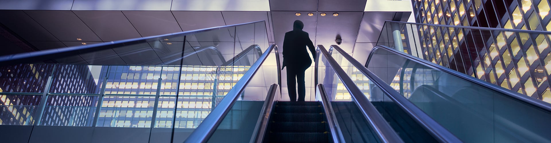Businessman on top of moving escalator at modern illuminated business district