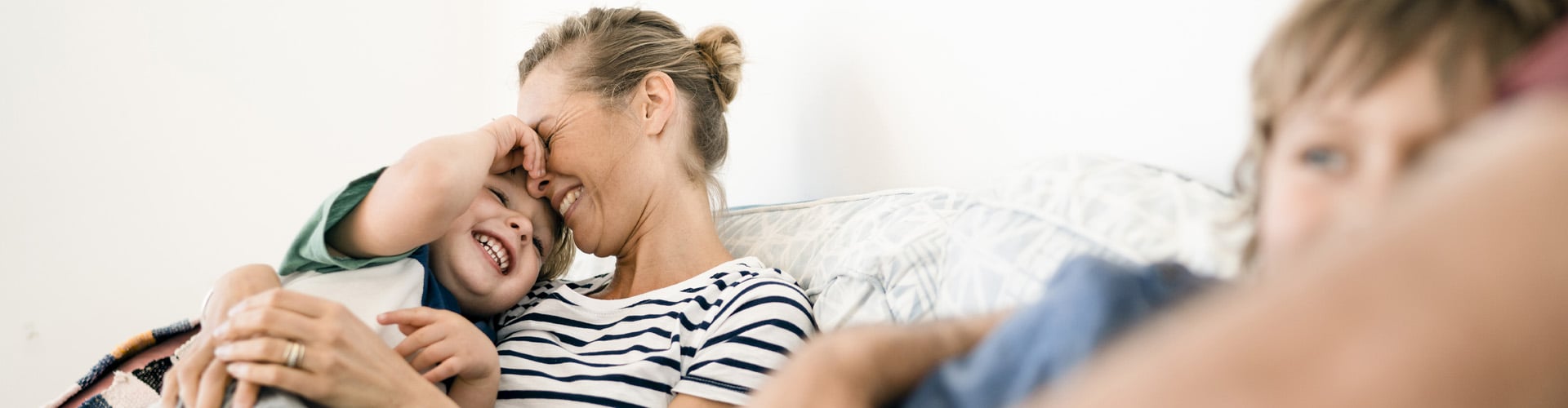 Mother and daughter hugging on the sofa and laughing