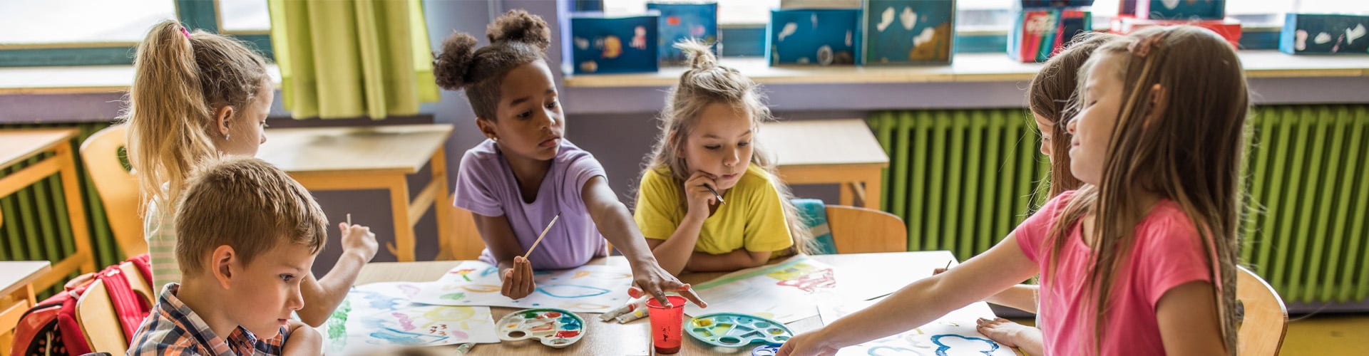 Group of diversity school children learning to paint together in art class