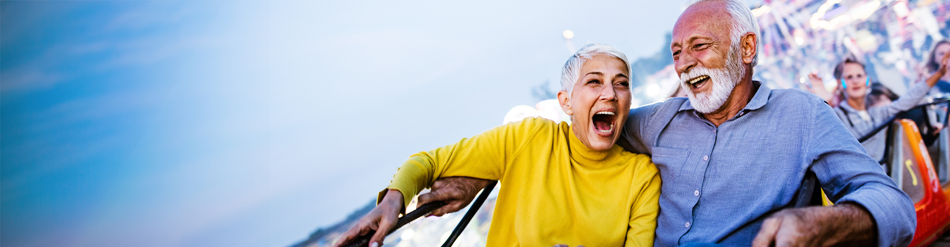 Old man and woman smiling riding a rollercoaster
