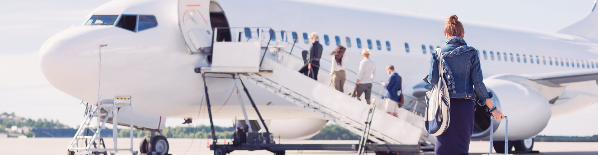 Woman walking towards a plane carrying suitcase
