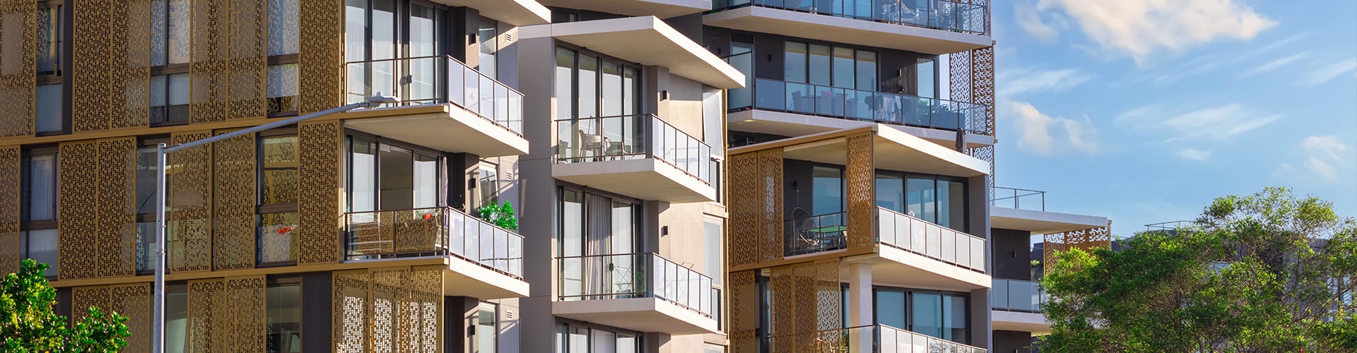 Modern residential building with several balconies and a façade under a clear blue sky