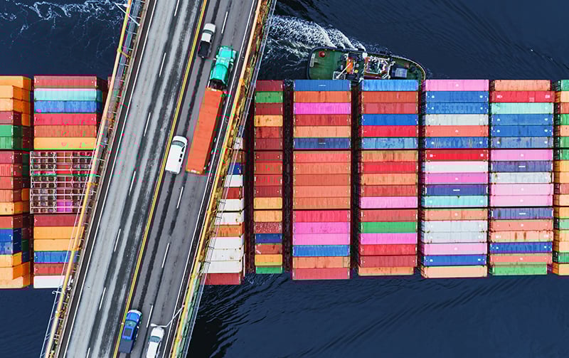 Aerial view of vehicles driving over cargo ship at sea