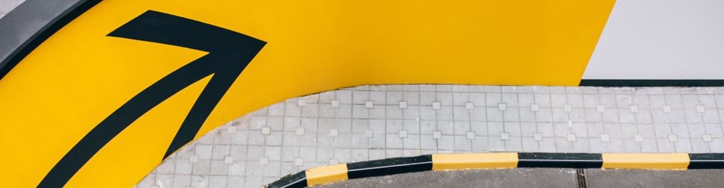 A yellow arrow painted on the gray tarmac of a street
