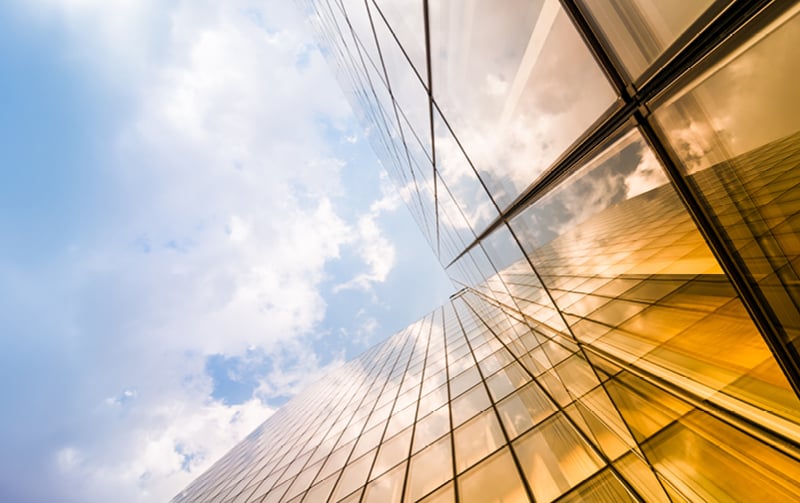 View looking up a glass office building with the light reflecting on it