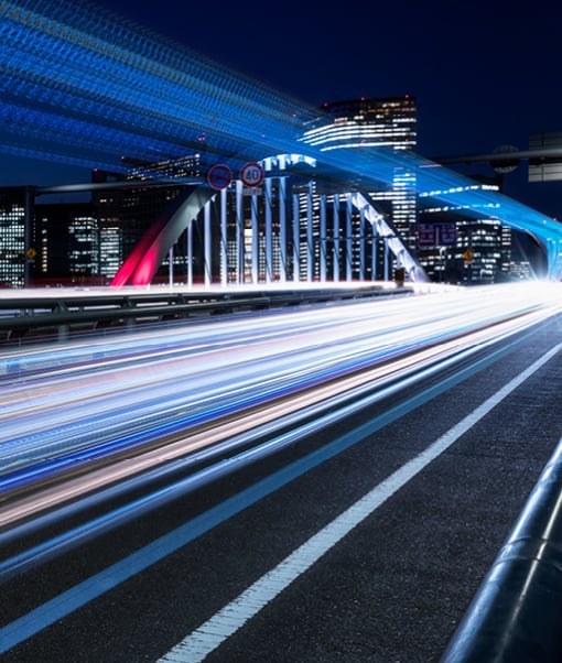 Track going over a bridge against city backdrop at night