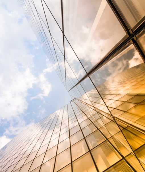 View looking up a glass office building with the light reflecting on it