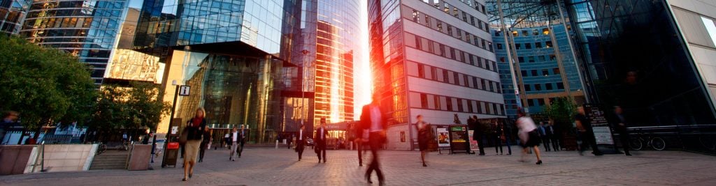 People walking through office blocks at sunrise