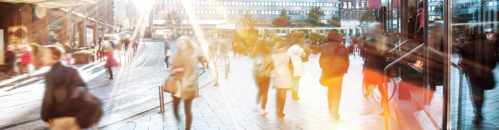 People walking through city centre on a bright day