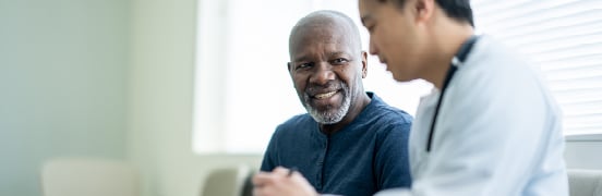 Young man and older man chatting in a light office room