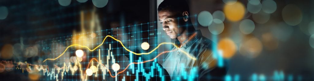 Man looking at investment charts against dark background
