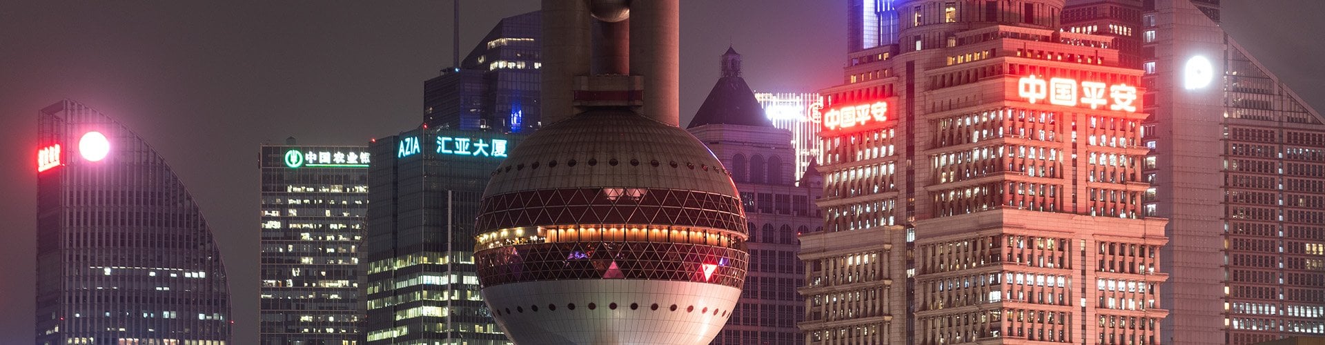 Shanghai skyline at night with the Oriental Pearl Tower and illuminated skyscrapers.