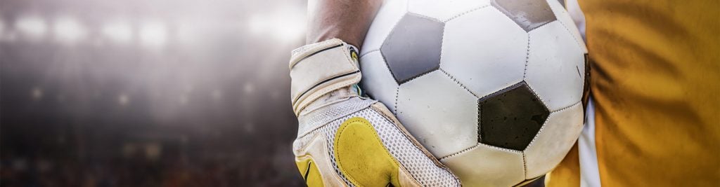 Close-up of a goalkeeper wearing gloves and holding a football
