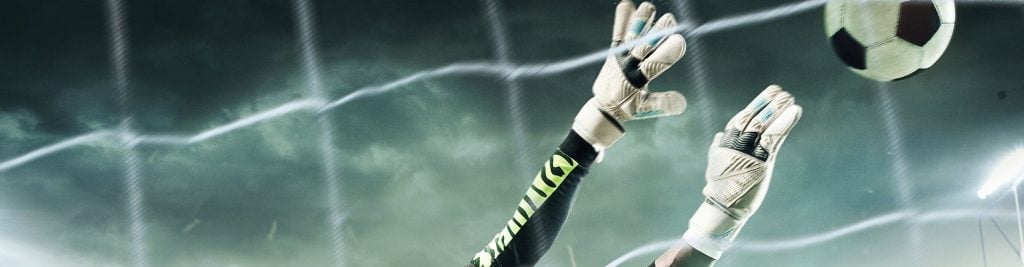 Goalkeeper reaching to save a football in front of the goal net