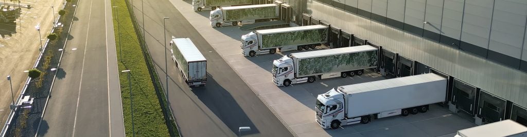Aerial view of lorries parked in an industrial car park by the side of the road