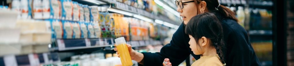 Woman and child looking at a drink in supermarket aisle