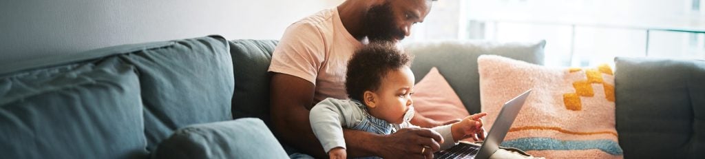 Man with baby on his lap looking at laptop screen