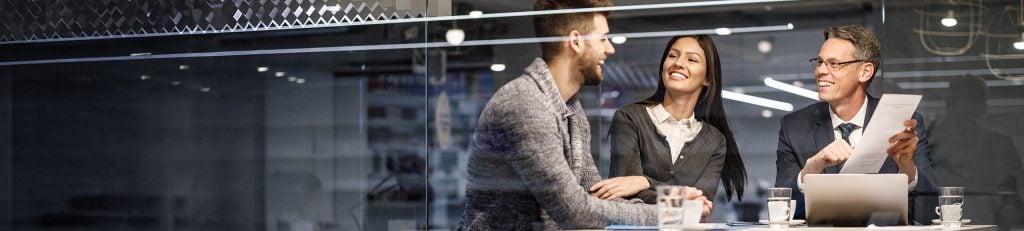 Man and woman laughing with Financial Adviser in meeting room