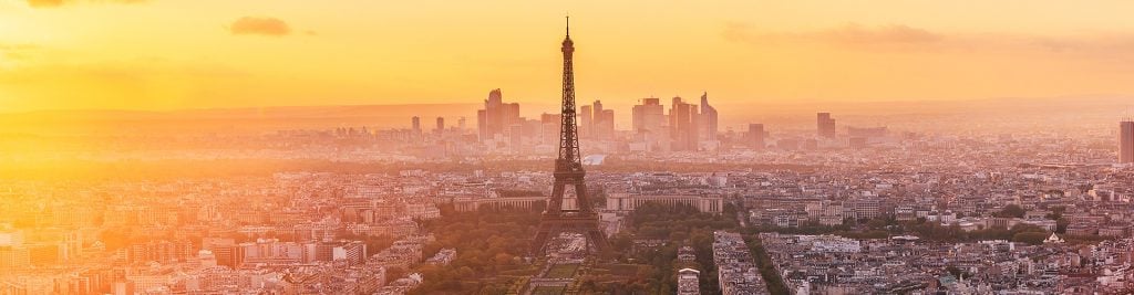 Eiffel Tower overlooking Paris at sunset with a golden city skyline.